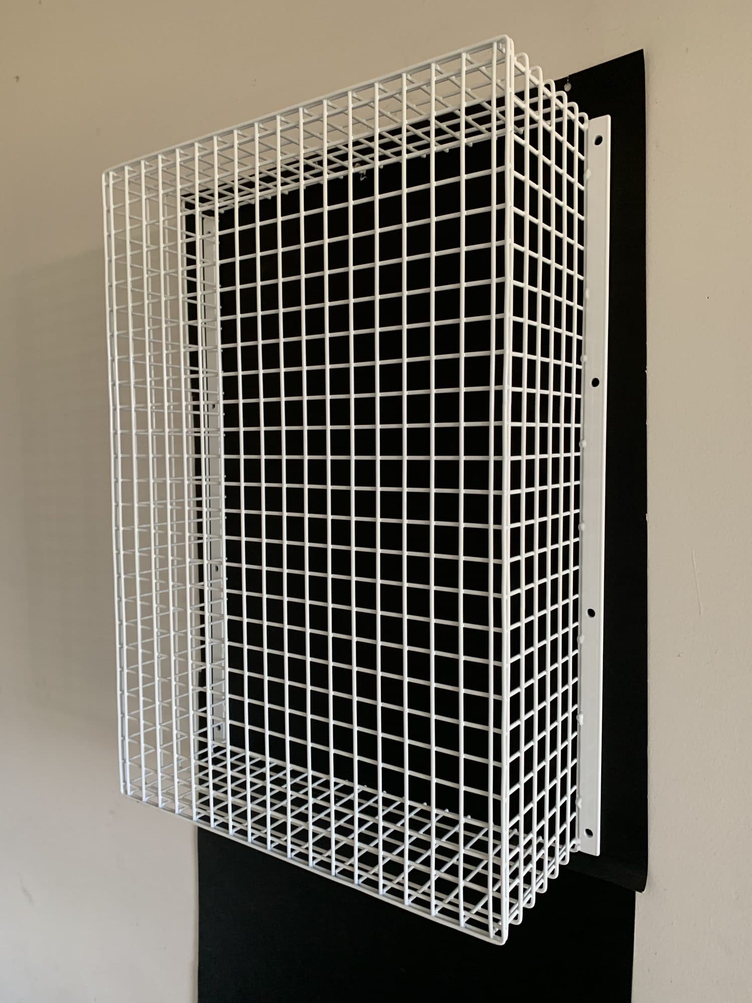 White wall-mounted wire mesh guard on a backing plate